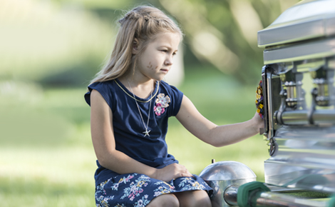 Young girl touching casket outside